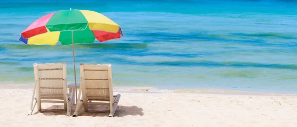 Панорама тропического пляжа со стульями и зонтиком — стоковое фото