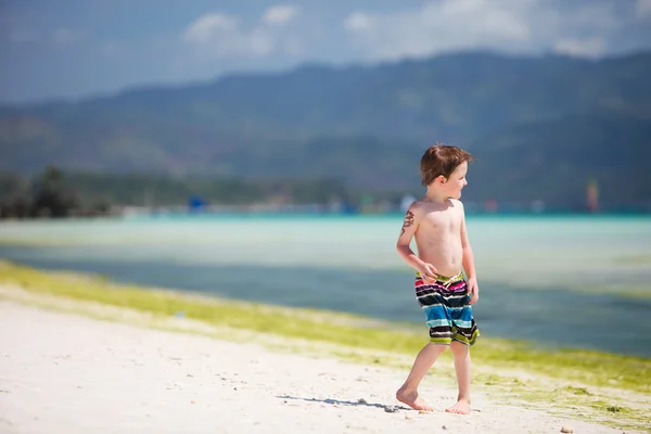 Liten pojke står vid havet stranden — Stockfoto