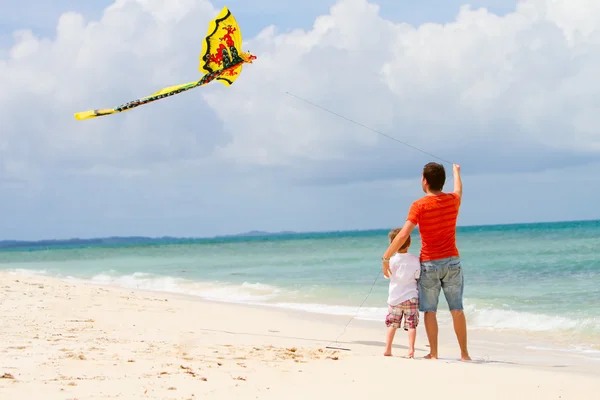 Отец и сын запускают воздушного змея на пляже — стоковое фото