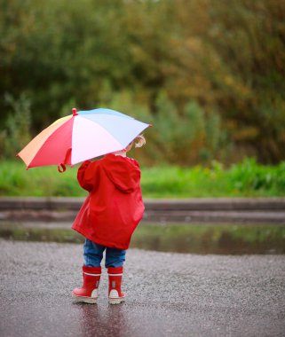 Toddler girl outdoors at rainy day clipart