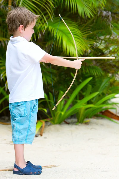 Милый мальчик играет с луком и стрелами — стоковое фото