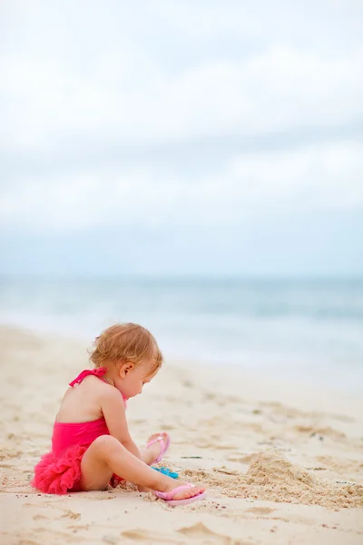 Toddler girl playing with toys at beach — Stockfoto