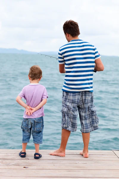 Отец и сын рыбачат с пирса — стоковое фото