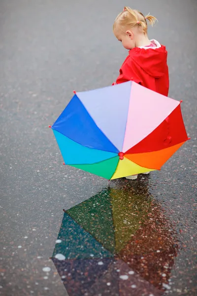 Toddler girl with colorful umbrella on rainy day Stock Image