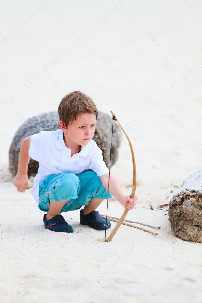 Cute boy playing with bow and arrows