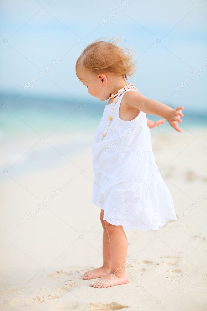 Toddler girl in white dress at beach