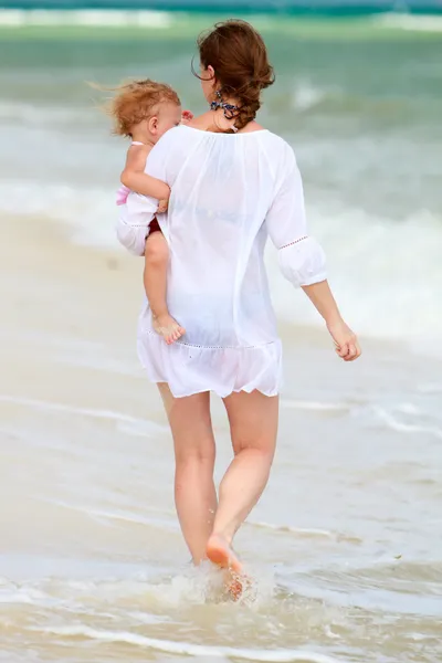 Mère et bébé marchant le long de la plage — Photo