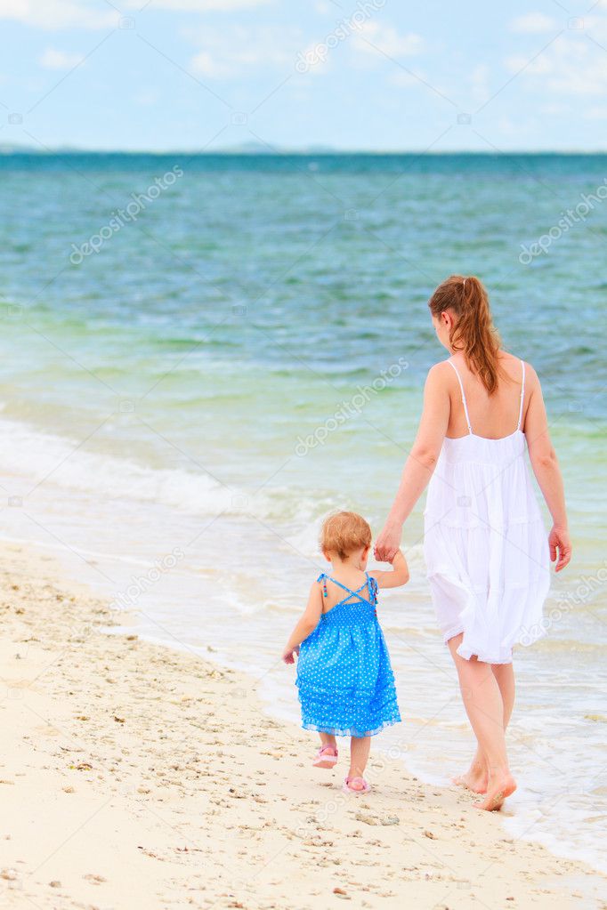 Mother and baby walking along tropical beach