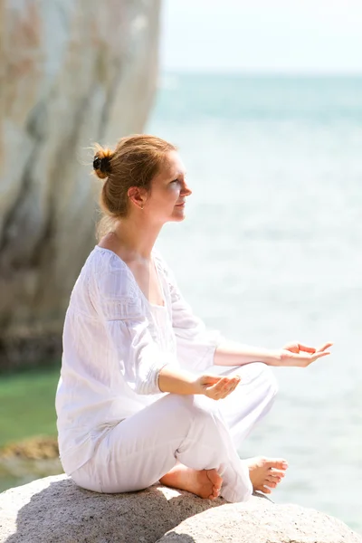 Jonge vrouw beoefenen van yoga door kust — Stockfoto