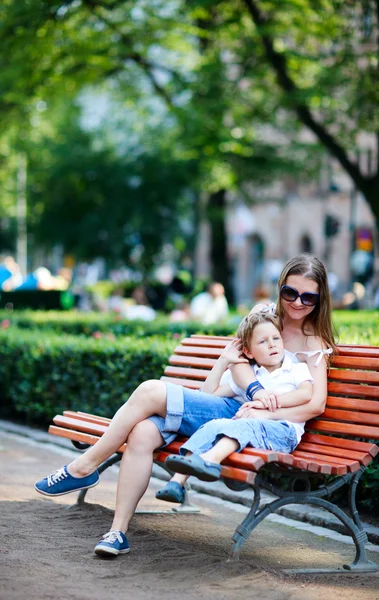 Mor och son på bänk i parken — Stockfoto