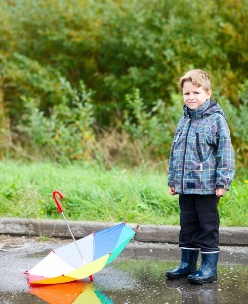 Мальчик с зонтиком в луже — стоковое фото