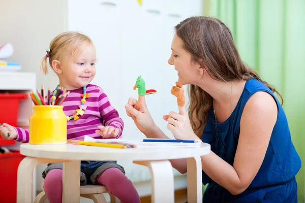 Mother and daughter playing with finger toys — Stock Photo, Image