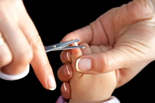 Мать стрижет ногти ножницами — стоковое фото