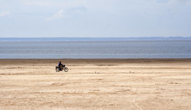 Riding biker on the beach clipart