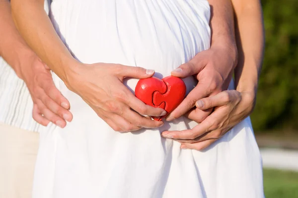 Живіт вагітної серцем в руках — стокове фото