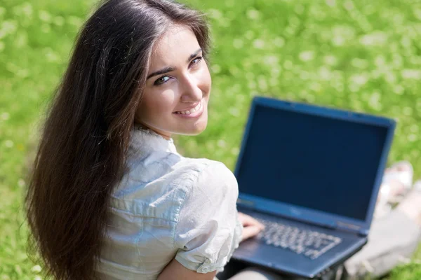 Jonge vrouw met laptop op gras — Stockfoto