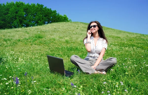 Mooie vrouw met laptop en mobiele telefoon zitten op heuvelbella mujer con portátil y teléfono móvil sentarse en colina — Stockfoto