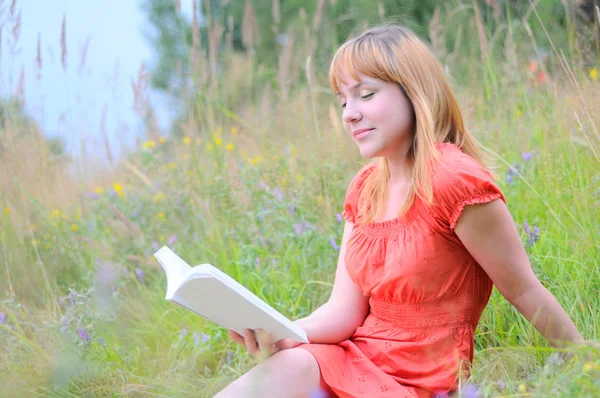 Mladá usměvavá žena čte knihu. — Stock fotografie