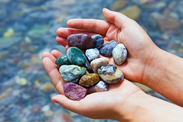 Kleurrijke stenen in handen Stockfoto