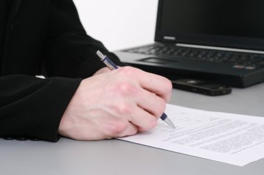 Man's hand with pen writing down notes with laptop on background clipart