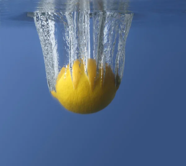 Hava kabarcıkları ile siyah / mavi arka planda suda taze limon — Stok fotoğraf