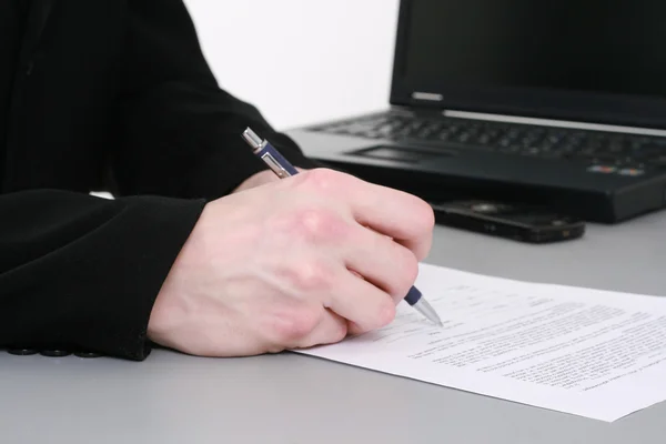Man's hand with pen writing down notes with laptop on background — Stock Photo, Image