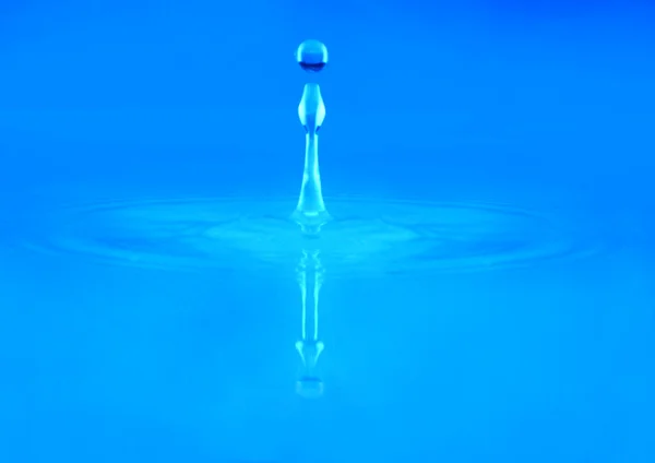 Splash água sobre um fundo azul — Fotografia de Stock