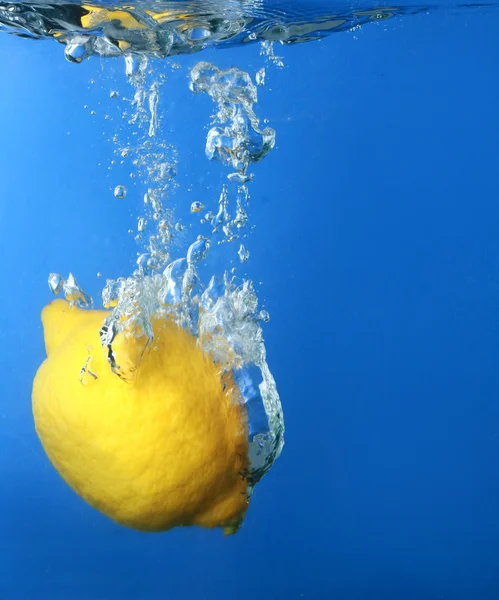 Свежий лимон упал в воду со сплюсом — стоковое фото