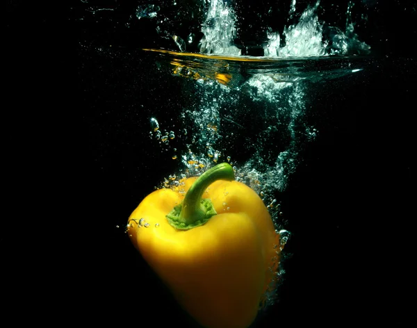 Gele peper in zwarte water — Stockfoto