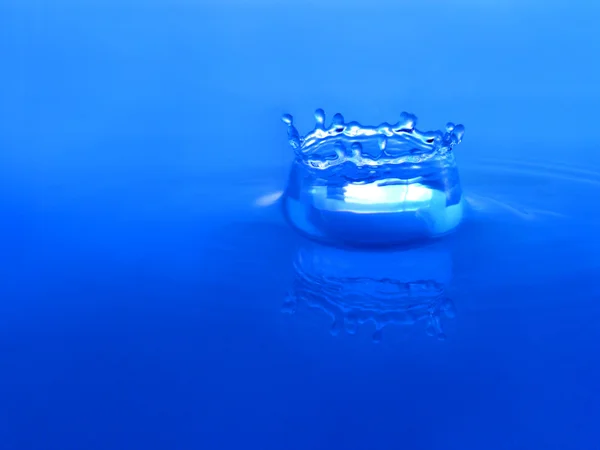Centelhas de água azul em um fundo azul — Fotografia de Stock