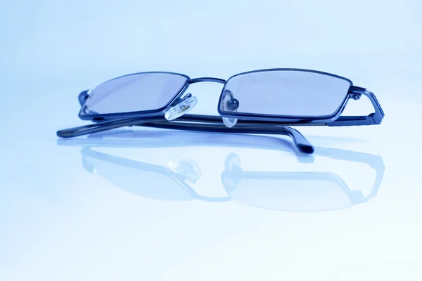 Gafas aisladas sobre fondo azul claro y reflexión Imagen de archivo