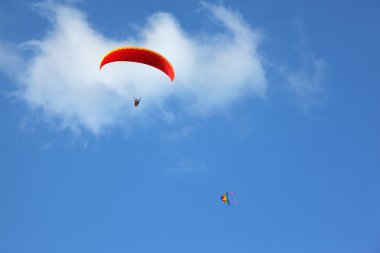 The red parachute flies in the blue sky clipart