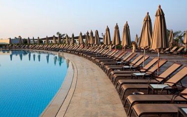 Chaise longue and umbrellas near the pool. clipart