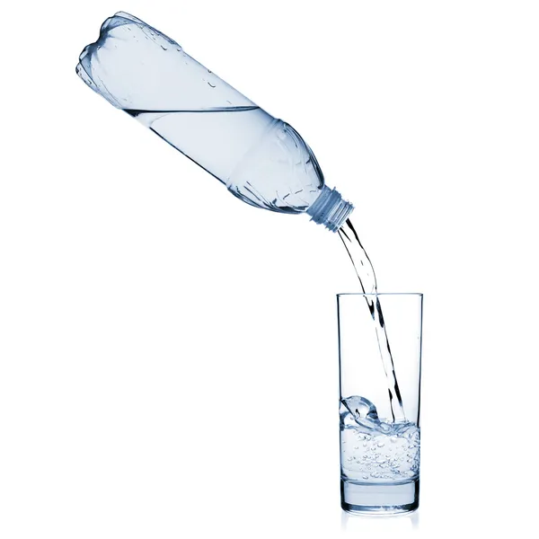 A água é derramada em vidro de uma garrafa — Fotografia de Stock