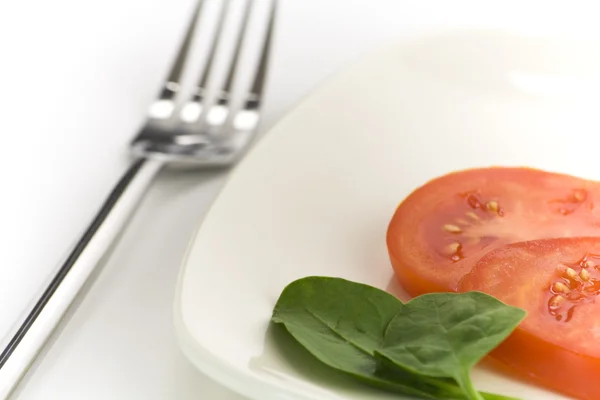Špenát a rajčata na bílé desce — Stock fotografie
