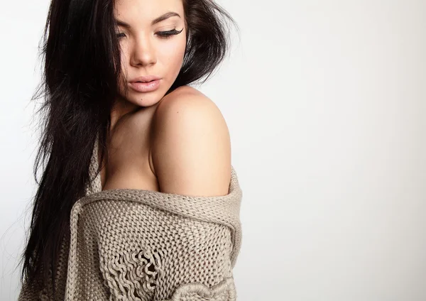 Mooie jonge brunette in een wollen trui vormen op een grijze bac — Stockfoto