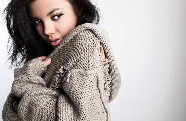 Όμορφη νεαρή μελαχρινή σε ένα μάλλινο πουλόβερ που θέτουν σε μια γκρίζα bac — Φωτογραφία Αρχείου