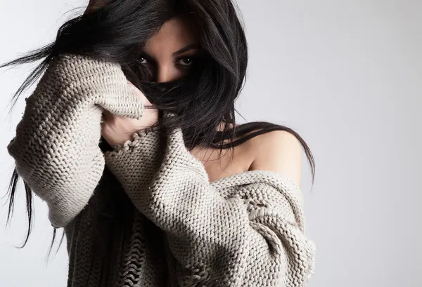 Όμορφη νεαρή μελαχρινή σε ένα μάλλινο πουλόβερ που θέτουν σε μια γκρίζα bac — Φωτογραφία Αρχείου