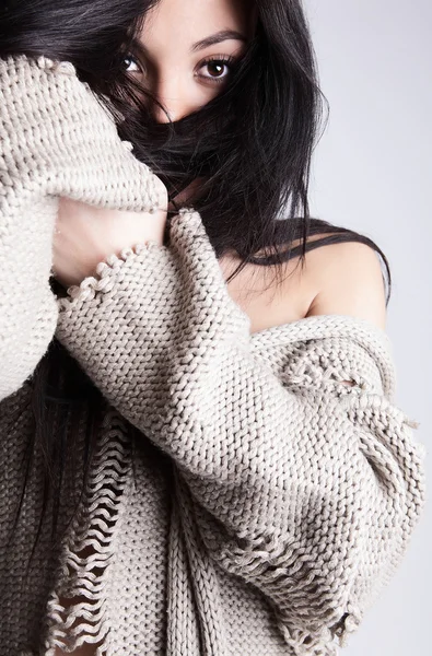 Belle jeune brune dans une pose de pull en laine sur un bac gris — Photo