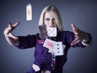 Blonde in violet on a grey background scatters playing cards. clipart