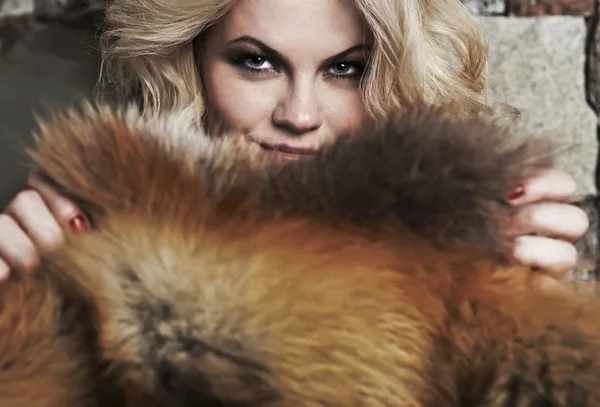 Blonde een relaxa in de buurt van een open haard opleggen fox skins — Stockfoto
