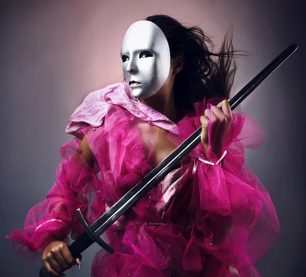 Vrouw krijger in een zilveren masker met een zwaard in handen. — Stockfoto