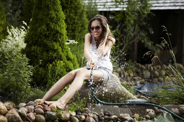 Gelukkig jonge vrouw met tuin stroming ontspannen in de buurt van de vijver. — Stockfoto