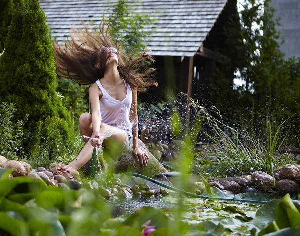 Glückliches junges Weibchen mit Gartenbächlein entspannt am Teich. — Stockfoto