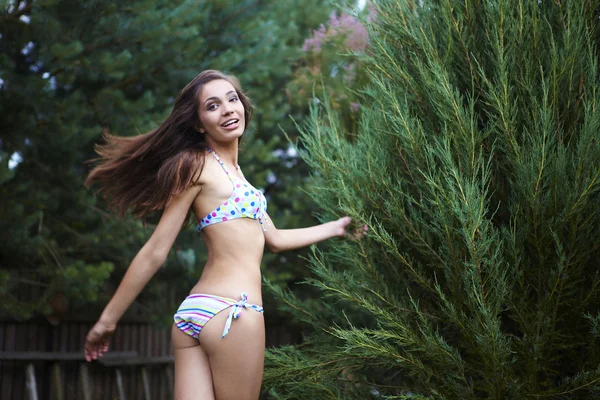 Chica atractiva feliz en traje de baño corriendo en el jardín . — Foto de Stock