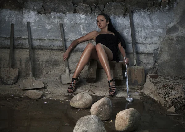 Sexual girl in black dress inside stone quarry among old shovels — Stock Photo, Image