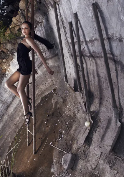 Seksuele meisje opleggen aan een roestige ladder van leider in een concrete fou — Stockfoto
