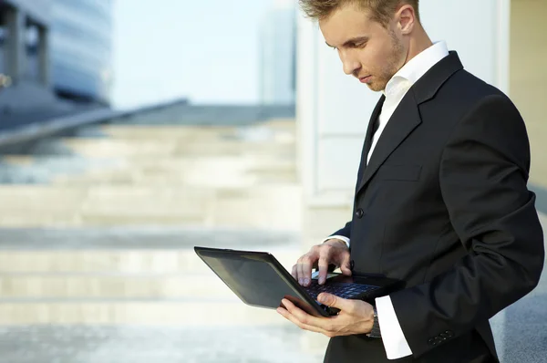 Closeup portrait of young businessman using laptop on street — Stock Photo, Image