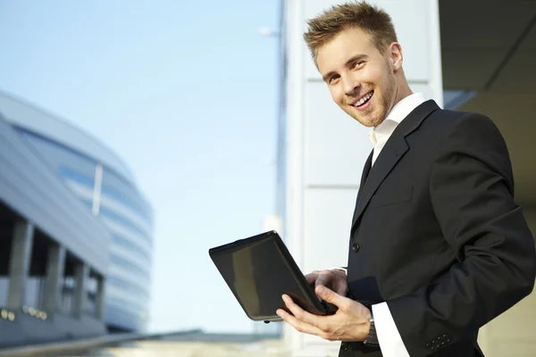 Closeup portrait of a happy young businessman using laptop on street — Stock Photo, Image
