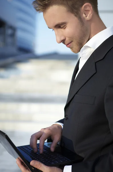 Крупним планом портрет щасливого молодого бізнесмена, що використовує ноутбук на вулиці — стокове фото